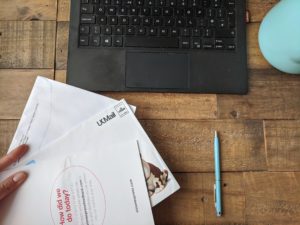 postal services results: hand holds a pile of direct mail envelopes